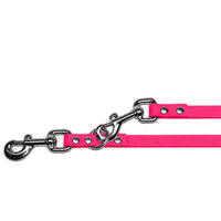 Detail: zwei Karabiner mit Wirbel und Nieten, einer im Ring eingehakt, an der Verlängerungsleine in Neon-Pink