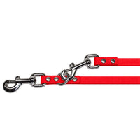 Detail: zwei Karabiner mit Wirbel und Nieten, einer im Ring eingehakt, an der Verlängerungsleine in Rot