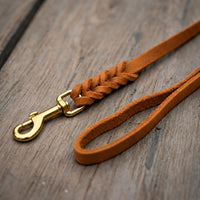 Detail: Fettlederleine in Cognac auf Holzdielen, geflochtenes Ende mit Messingkarabiner und Handschlaufe