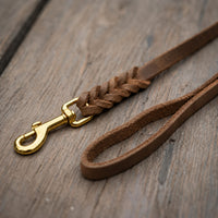 Detail: Fettlederleine in Braun auf Holzdielen, geflochtenes Ende mit Messingkarabiner und Handschlaufe