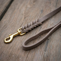 Detail: Fettlederleine in Grau auf Holzdielen, geflochtenes Ende mit Messingkarabiner und Handschlaufe
