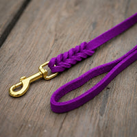 Detail: Fettlederleine in Lila auf Holzdielen, geflochtenes Ende mit Messingkarabiner und Handschlaufe