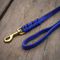 Detail: Fettlederleine in kräftigem Blau auf Holzdielen, geflochtenes Ende mit Messingkarabiner und Handschlaufe
