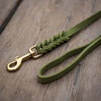 Detail: Fettlederleine in Oliv auf Holzdielen, geflochtenes Ende mit Messingkarabiner und Handschlaufe
