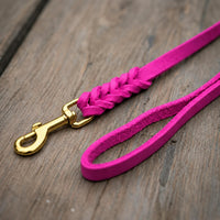Detail: Fettlederleine in Pink auf Holzdielen, geflochtenes Ende mit Messingkarabiner und Handschlaufe
