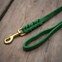 Detail: Fettlederleine in Tannengrün auf Holzdielen, geflochtenes Ende mit Messingkarabiner und Handschlaufe