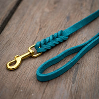 Detail: Fettlederleine in Türkis auf Holzdielen, geflochtenes Ende mit Messingkarabiner und Handschlaufe