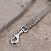 Detail: geflochtenes Ende mit Edelstahlkarabiner an Fettlederleine in Grau auf Sand
