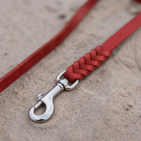 Detail: geflochtenes Ende mit Edelstahlkarabiner an Fettlederleine in Rot auf Sand