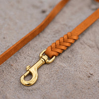 Detail: geflochtenes Ende mit Messingkarabiner an Fettlederleine in Cognac auf Sand