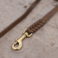 Detail: geflochtenes Ende mit Messingkarabiner an Fettlederleine in Braun auf Sand