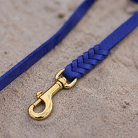 Detail: geflochtenes Ende mit Messingkarabiner an Fettlederleine in kräftigem Blau auf Sand