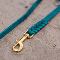 Detail: geflochtenes Ende mit Messingkarabiner an Fettlederleine in Türkis auf Sand
