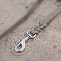 Detail: Chrom-Karabiner und Flechtverbindung einer Fettlederleine in Grau auf Sand