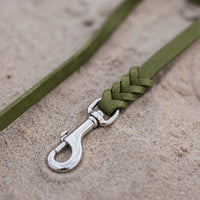 Detail: Chrom-Karabiner und Flechtverbindung einer Fettlederleine in Oliv auf Sand