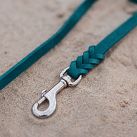 Detail: Chrom-Karabiner und Flechtverbindung einer Fettlederleine in Türkis auf Sand