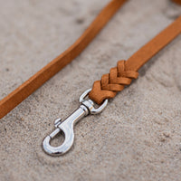 Detail: Edelstahl-Karabiner und Flechtverbindung einer Fettlederleine in Cognac auf Sand