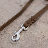 Detail: Edelstahl-Karabiner und Flechtverbindung einer Fettlederleine in Braun auf Sand