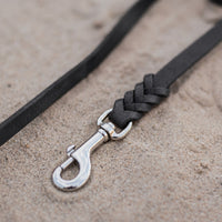 Detail: Edelstahl-Karabiner und Flechtverbindung einer Fettlederleine in Schwarz auf Sand